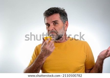 Anosmia or smell blindness, loss of the ability to smell, one of the possible symptoms of covid-19, infectious disease caused by corona virus. Man Trying to Sense Smell of a Lemon Royalty-Free Stock Photo #2110500782