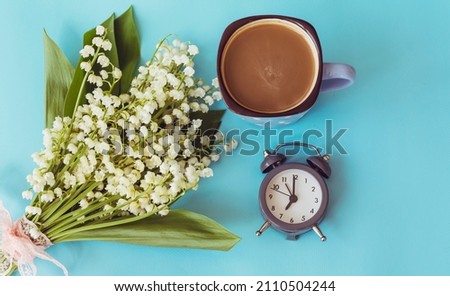 Lily of the valley bouquet ,cup of Coffee and clock  for good morning .Spring Morning Concept
