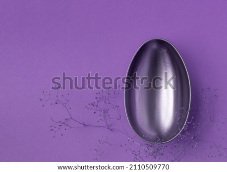 shiny egg and delicate flowers on a purple background. Easter background or easter concept. copy space