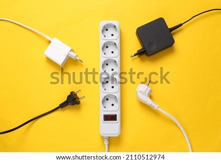 Electrical Extension cord with different plugs and adapters on yellow background. Top view. Royalty-Free Stock Photo #2110512974