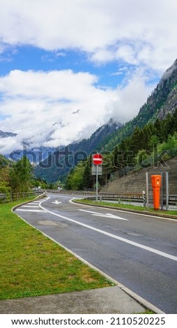 Stop sign on asphalt road in Swiss alpine mountains, summer, sunny day	