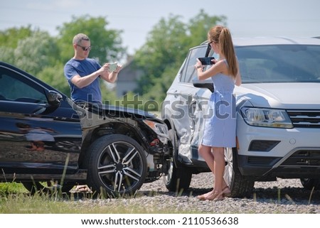 Stressed drivers taking picture on sellphone camera of smashed vehicles calling for emergency service help after car accident. Road safety and insurance concept