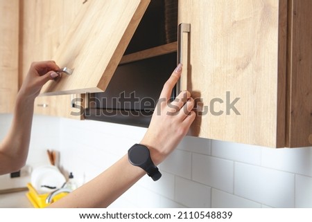 Caucasian woman opens the kitchen door furniture. Royalty-Free Stock Photo #2110548839