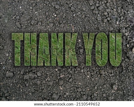 The words "thank you" written in grassy letters on dry black ground