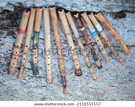Top view of shakuhachi flutes. They leaned against a beautiful stone wall. They stand at an angle of about 30 degrees. The flutes are handmade from bamboo. There are cracks in the rocks below