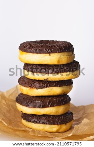 
Donuts with chocolate icing and chocolate chips on a light background. Donuts on craft paper are located on top of each other. Close-up.

