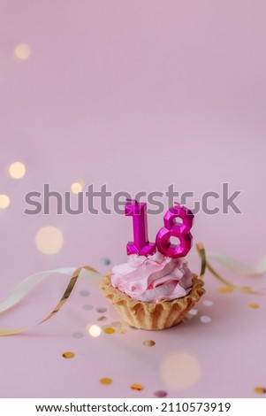 a beautiful picture of a cupcake with pink butter cream and cherry with a number 18 candles on the top of it. Festive Happy birthday mood. Card design idea. coming of age