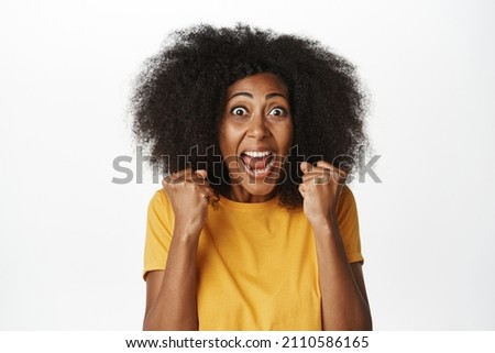 Portrait of enthusiastic black woman looking excited and amazed, achieve goal, celebrating victory and triumphing, shouting with joy, white background