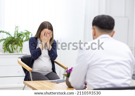 Photo of pregnant woman speaking with a doctor.