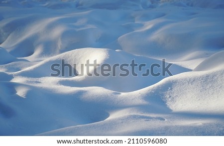 snowdrift, a snowy plain in the sun. winter wave Royalty-Free Stock Photo #2110596080