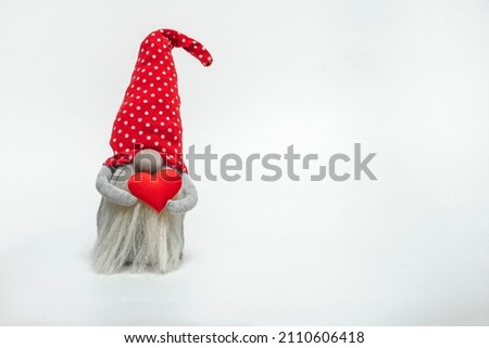 Dwarf in a red hat with a red heart in his hands isolated on a white background. Idea for valentine's day