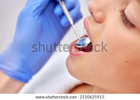 Side view close up portrait of cute child girl getting dental checkup at dentistry. Dentist using dental equipment for examination checkup of teeth of female kid patient sitting on chair Royalty-Free Stock Photo #2110625915