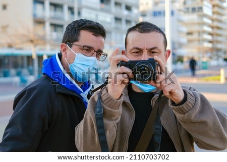 Two men taking pictures with a professional reflex camera.
