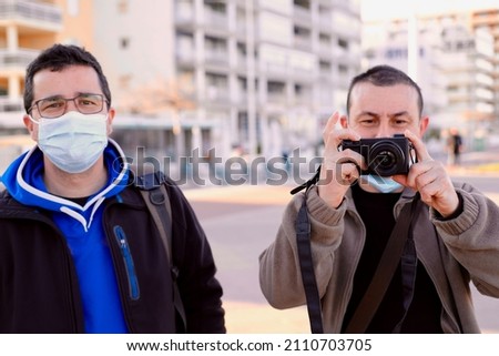 Two men taking pictures with a professional reflex camera.
