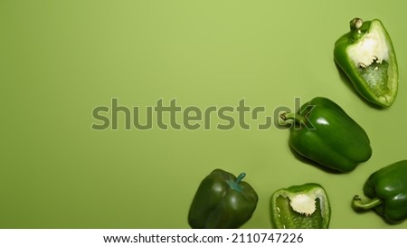 Fresh whole and sliced sweet pepper isolated on green background.