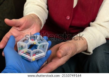Close up picture of elderly hands holding a plastic container with pills 