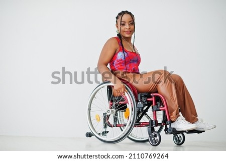 Young disabled African American woman in wheelchair against white wall. Royalty-Free Stock Photo #2110769264