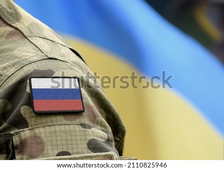 Flag of Russia on military uniform and flag of the Ukraine at background. Russia VS Ukraine. Royalty-Free Stock Photo #2110825946