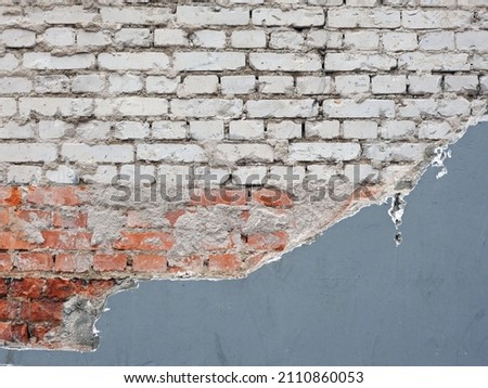 
Fragment of an old brick wall with grey-colored plaster with chipped plaster. Close-up.					