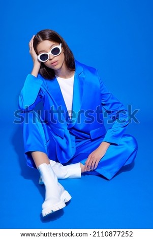 Fashion asian female model in blue suit, white boots and sunglasses. Asian fashion Royalty-Free Stock Photo #2110877252