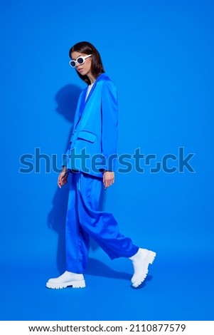 Fashion asian female model in blue suit, white boots and sunglasses. Asian fashion Royalty-Free Stock Photo #2110877579