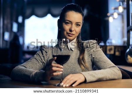 Beautiful girl drinks wine from a glass in a restaurant, a cafe, has a good weekend, a stylish fashionable woman, a brunette young, emotional, outdoor. Close up. Royalty-Free Stock Photo #2110899341