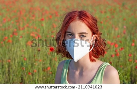 frustrated young girl with protective mask in poppy field