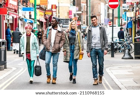 Multicultural students walking on Brick Lane center at Shoreditch London - Life style concept with multi-ethnic young friends on seasonal clothes having fun together outside - Bright vivid filter Royalty-Free Stock Photo #2110968155