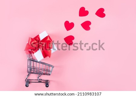 Flat lay. Shopping cart for purchases, gifts on a pink background. The concept of delivery of gifts and parcels for the holidays valentines day, pleasant surprises. Shopping, sale, promotion.