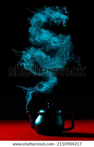 Chinese New Year magic composition on classy red table and elegant black teapot steaming a dragon silhouette.