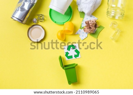 Clean trash to recycle in small bin metal, plastic paper and glass. Recycling concept on yellow.
