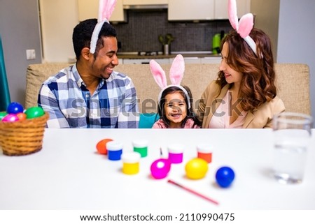 multicultural family painting eggs in cozy kitchen