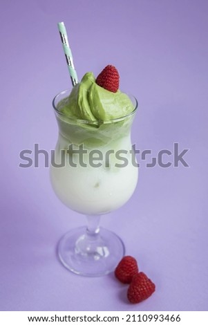 Dalgona matcha  and raspberries  on a very peri  background . Trendy drink . Superfoods . Dairy beverage .  Purple background .