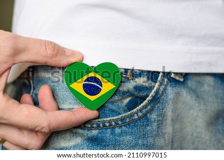 Brazilian resident. Wooden badge with Brazil flag in the shape of a heart in a man's hand.