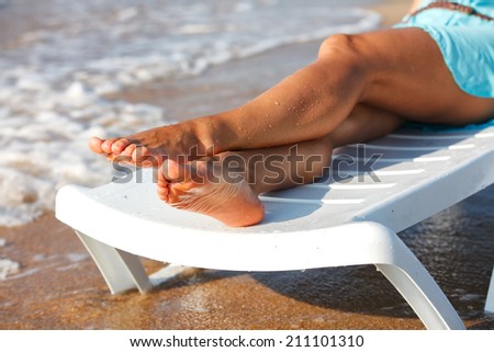 Vacation holidays. Woman feet closeup of girl relaxing on beach on sunbed enjoying sun on sunny summer day. 