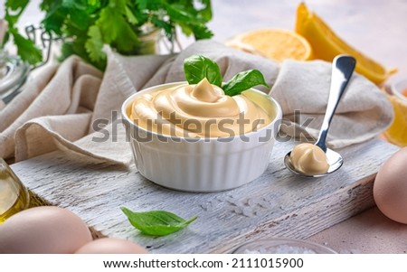 Mayonnaise and natural ingredients on a light background. Side view, close-up. Royalty-Free Stock Photo #2111015900