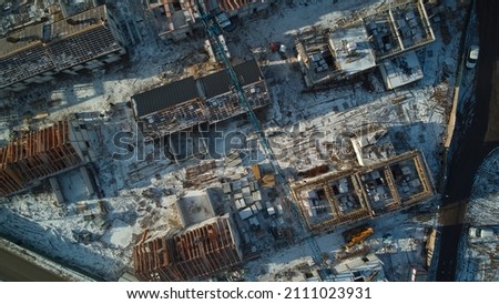 Aerial drone: Building construction site, crane, development of new areas, building new house construction crane moves materials, winter