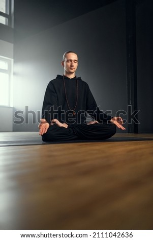 The yogi man meditate in the lotus position with gyan mudra. Yoga practice in the studio. Royalty-Free Stock Photo #2111042636