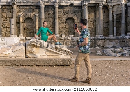 couple of tourists take pictures of each other among the antique ruins