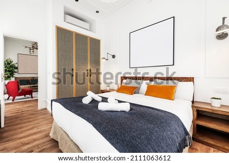 King-size bed in furnished short-term rental apartment with upholstered cupboard doors and decorative cushions Royalty-Free Stock Photo #2111063612