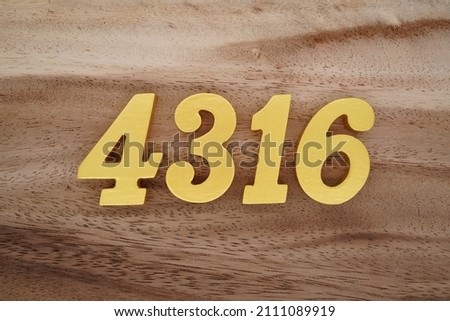 Wooden Arabic numerals 4316 painted in gold on a dark brown and white patterned plank background.