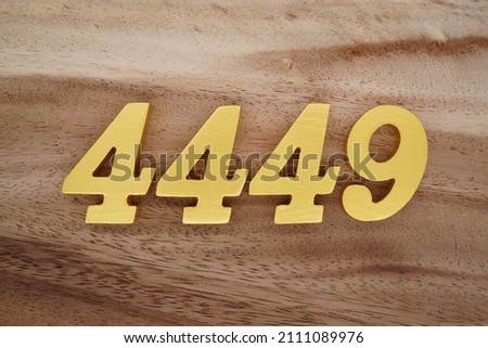 Wooden Arabic numerals 4449 painted in gold on a dark brown and white patterned plank background. Royalty-Free Stock Photo #2111089976