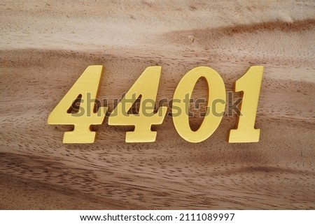 Wooden Arabic numerals 4401 painted in gold on a dark brown and white patterned plank background.