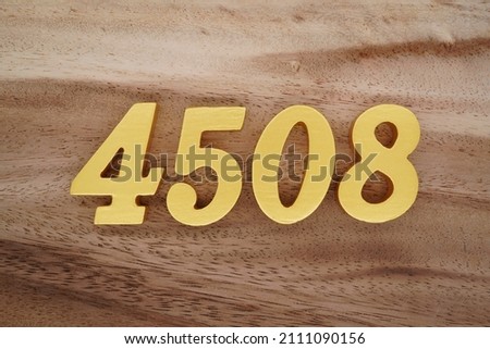 Wooden Arabic numerals 4508 painted in gold on a dark brown and white patterned plank background.