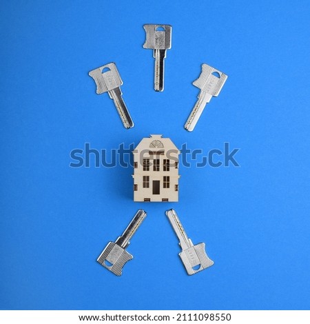 Conceptual photo: House keys and a model of a European house on a colored background. Top view, flat lay. The concept of buying and selling housing.