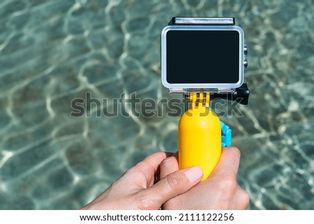 Close-up, Mockup of an action camera with a yellow float. against the backdrop of a pool of water