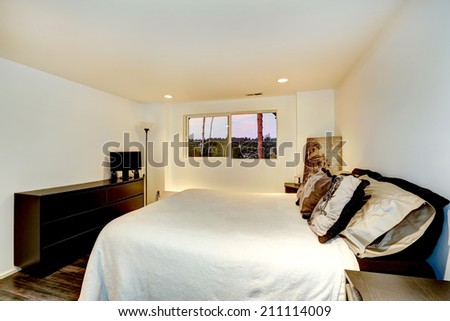 White bedroom interior with dark dresser and queen size bed