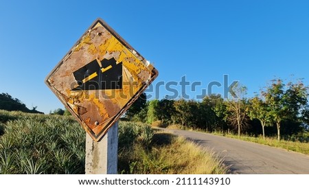 The yellow traffic sign has a black ramp. The condition is so old that there is rust and the plastic coating has peeled off. 