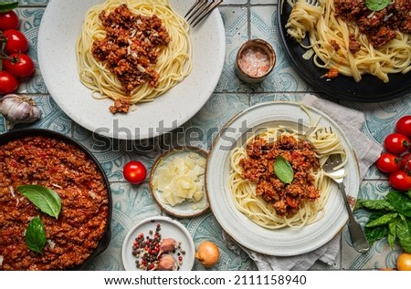 Pasta spaghetti bolognese with minced beef sauce, tomatoes, parmesan cheese and fresh basil in a plate on tile background. Italian food, top view