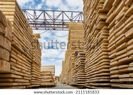 Rough sawn timber from spruce and pine stacked in a sawmill inside a warehouse. Wooden background for text. Royalty-Free Stock Photo #2111181833